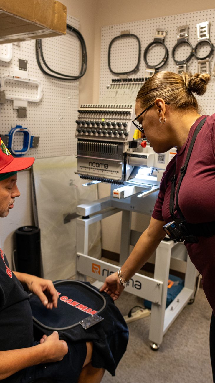 Two of the crew setting a garment on the embroidery machine